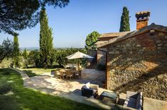 an outdoor patio with tables and chairs next to a stone building, surrounded by trees