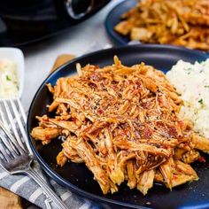 pulled pork with gravy and mashed potatoes on a black plate next to a fork