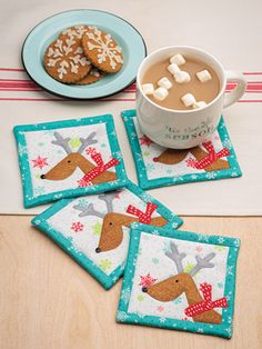 four coasters with reindeer designs on them and a cup of coffee