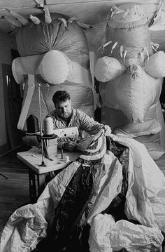 a black and white photo of a man working on a sewing machine in his studio