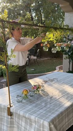 a man standing at a table with flowers on it and an umbrella over his head