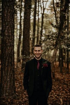 a man in a suit and tie standing in the woods