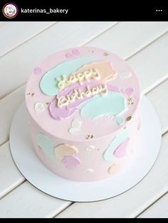 a pink birthday cake sitting on top of a white wooden table next to a sign that says happy birthday