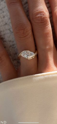 a woman's hand with a diamond ring on top of her finger and the bottom half of her wedding band