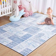 a baby sitting on the floor in front of a rug