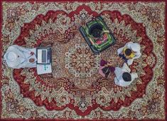 three people sitting at a table on top of a rug with laptops and papers