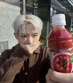 a man holding a bottle of ketchup next to his face