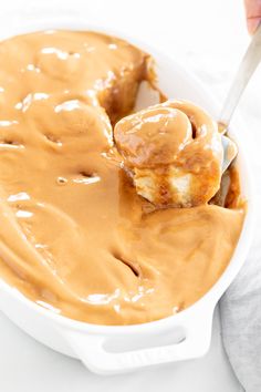 a spoonful of caramel sauce being scooped from a casserole dish with bread