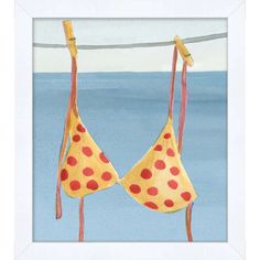 two bras hanging on a clothes line in front of the ocean, one with red polka dots