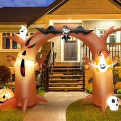 two inflatable halloween decorations are on the front lawn of a house at night