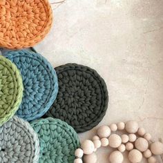 multicolored crocheted placemats and wooden beads on the floor with white background