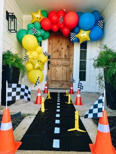 the entrance to a race themed house decorated with balloons and checkered tape, cones, and stars