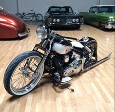 a motorcycle is parked in a garage with other cars on the floor and behind it