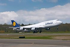 a large passenger jet taking off from an air port run way with trees in the background