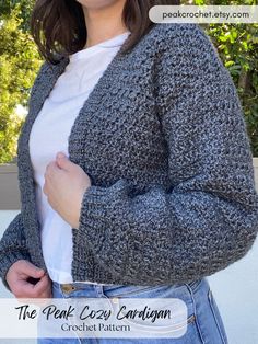 a woman is wearing a gray cardigan sweater and jeans with her hands in her pockets