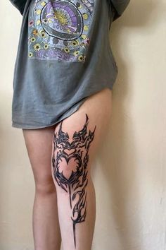 a woman with a tattoo on her leg is standing in front of a white wall