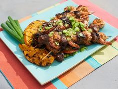 a blue plate topped with meat and veggies on top of a colorful table cloth