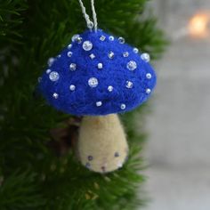 a blue mushroom ornament hanging from a christmas tree with white and silver beads