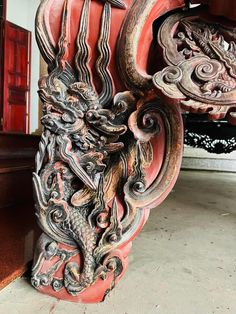 an intricately carved dragon sculpture on display in a room with red walls and wooden floors