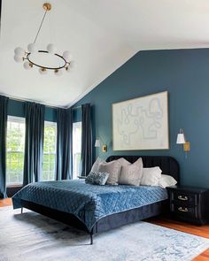 a bedroom with blue walls and wooden flooring, along with a large bed in the center