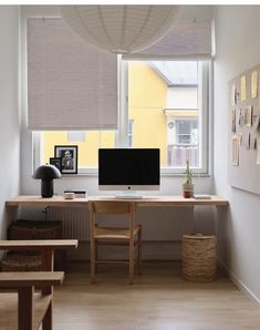 a desk with a computer on top of it in front of a window and some pictures