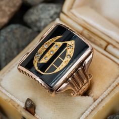 This fantastic antique initial ring features a a rectangular cut black onyx tab. The onyx is accented with the calligraphy letter "O" made with inlay high carat gold and diamond accents. The onyx has very small nicking at the edges. The ring is crafted in 10k yellow gold that has a rosy color to it. The gold has been left unpolished and with its rich natural patina. The inside of the ring is engraved "Emilcito." Luxury Men's Yellow Gold Onyx Ring, Luxury Rectangular Onyx Jewelry, Antique Black Enamel Signet Ring, Antique Signet Ring With Diamond Accents For Formal, Antique Signet Ring With Diamond Accents For Formal Occasions, Luxury Diamond Signet Ring Collectible, Elegant Signet Ring As Collectible, Art Deco Rectangular Signet Ring With Polished Finish, Antique Black Signet Ring Collectible