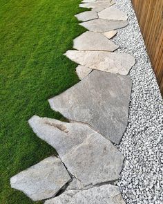 a stone path in the grass between two wooden fences