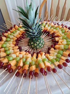 a pineapple and grapes arranged in a circle on skewers for a fruit platter