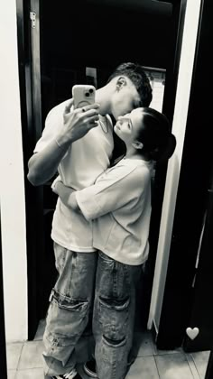 a man and woman are kissing in front of a mirror while looking at their cell phones