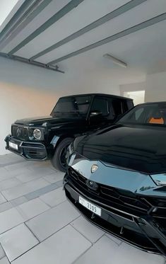 two black cars parked in a garage next to each other on the tile flooring