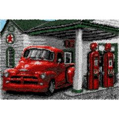 an old red truck is parked in front of a gas station with two fuel pumps