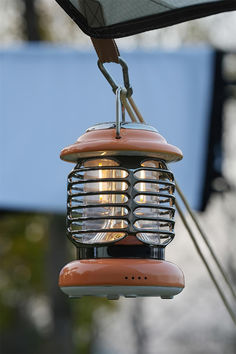 a bird feeder hanging from the side of a building with its light on it's head