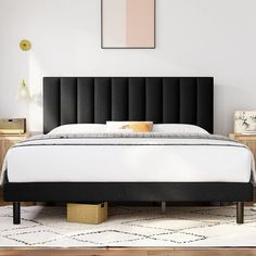 a bed with a black headboard sitting on top of a white carpeted floor