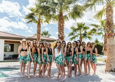 a group of young women standing next to each other in front of a palm tree