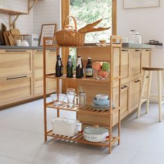 a kitchen filled with lots of counter space and wooden shelves next to a window covered in windows