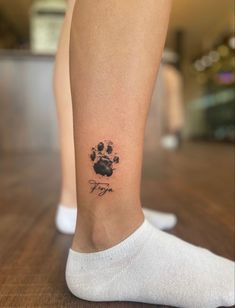 a person with a dog paw tattoo on their leg and foot, standing on a wooden floor