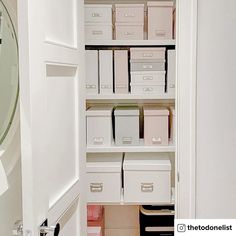 the closet is filled with lots of white boxes and file folders on shelving units