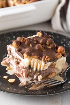 a piece of ice cream dessert on a black plate with a fork in front of it