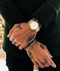 a man with tattoos on his arm and wrist wearing a watch, bracelets and other accessories