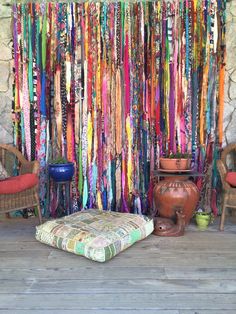 colorful ribbons hang from the ceiling in front of a stone wall and wicker chairs