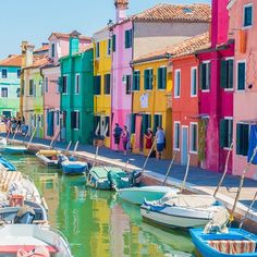 many boats are parked in the water next to some buildings with colorful paint on them