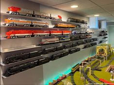 a toy train set is on display in a room with multiple shelves and lights above it