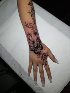 a woman's hand with flowers and leaves on the left side of her arm