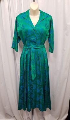 Vintage 1960s Lord & Taylor by Peer Gorgeous Satin Green and Blue Embroidered Floral Print Fit n Flare Party Dress w Matching Belt. The dress has a 2 button, 1 snap, hook & eye, and zipper front closure.  The dress has 2 side pockets, darts on the bodice, full pleated skirt, 3/4 sleeves, and a matching belt. Dress is in excellent condition...see pics!  Measurements: shoulder to shoulder 18, bust 36, waist 27, sleeves shoulder to cuff 13, sleeves pit to cuff 11, length 50 1/2, belt 77 inches. Cap Sleeve Gown, Vintage Overalls, Boho Festival Fashion, Pin Up Dresses, Belt Dress, 1940s Dresses, Party Dress Short, Vintage Gowns, Gowns With Sleeves