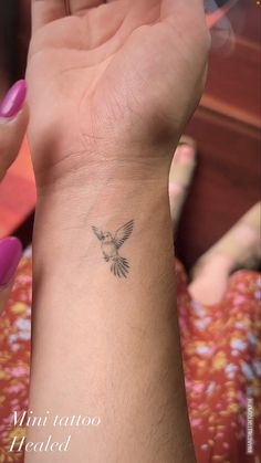 a woman's arm with a small bird tattoo on her left wrist and right hand