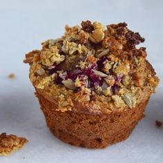 a muffin with crumbled toppings sitting on top of a white surface