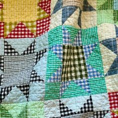 a close up of a quilt with many different colors and patterns on it, as well as stars