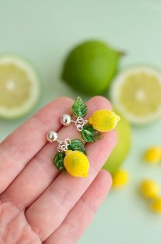 a person is holding two lemons in their hand and some limes are on the table behind them