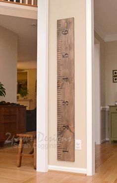 a tall wooden ruler sitting on top of a hard wood floor next to a stair case