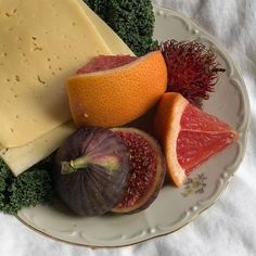 an assortment of cheeses, fruits and vegetables on a plate